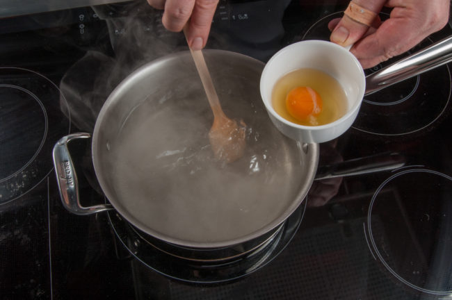 Eier pochieren, Wasser mit dem Kochlöffel in Drehbewegung versetzen - enos-Kochlexikon